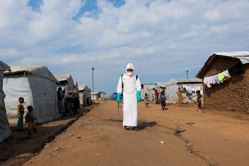 Health worker in PPE disinfecting an area during the burial of suspected Ebola victims at Kigonze displaced persons camp in Bunia, Democratic Republic of Congo.