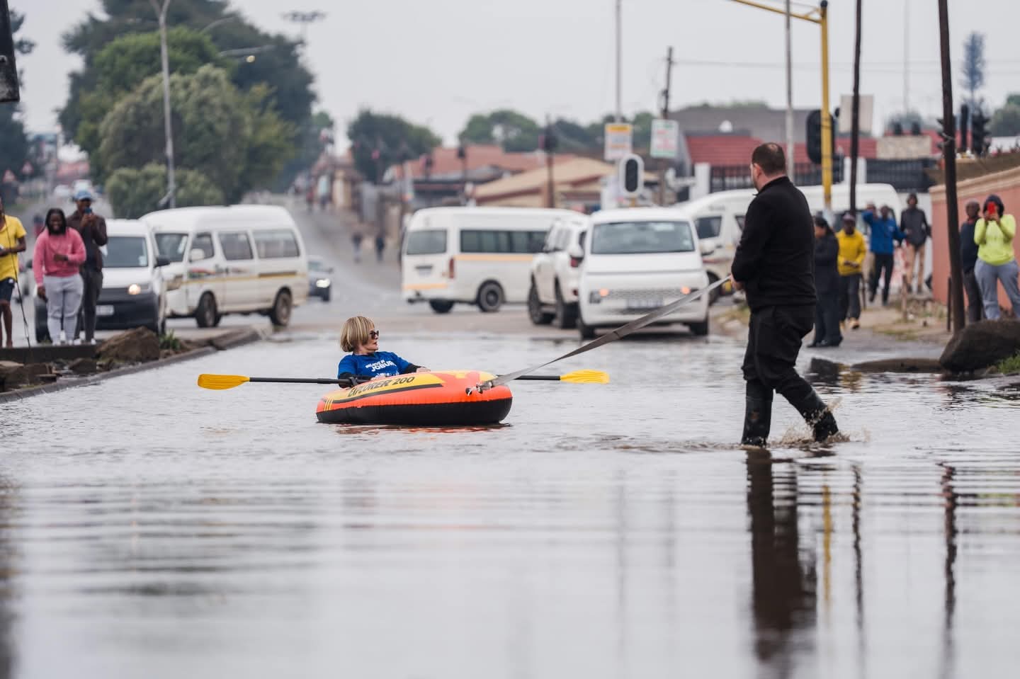 Helen Zille rowing a boat down a flooded street.